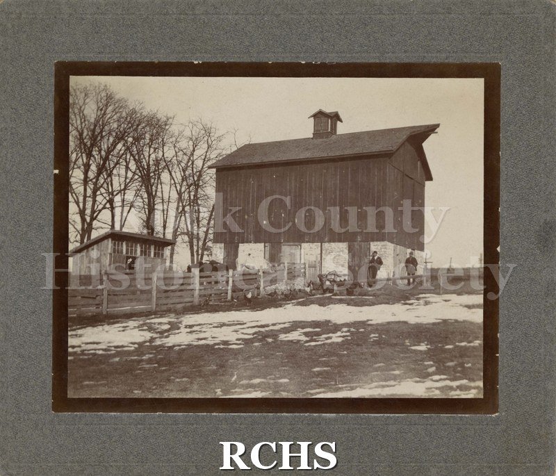 Black and white photograph of a farm view. Shows a wood and brick barn, probably in Rock County.