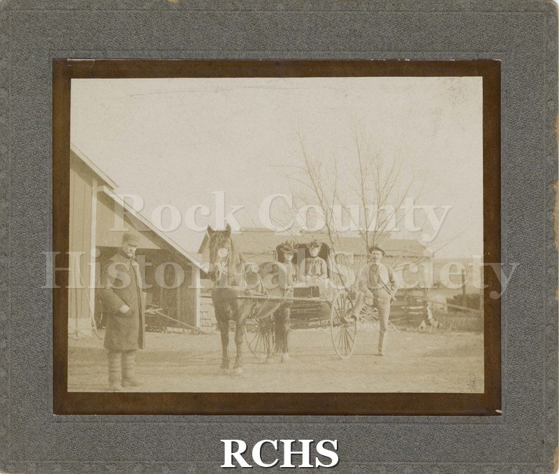 Black and white photograph of a horse and buggy with two women seated in it.