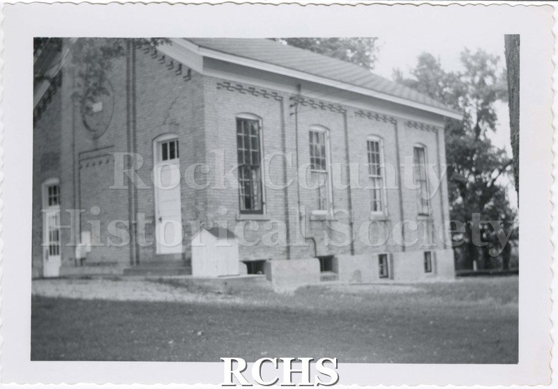 Black and white photograph of West Center School, on August 12, 1956. Woodshed (?) visible. Edges decoratively trimmed.