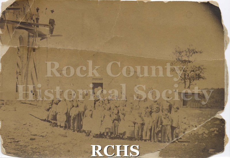 Black and white photograph of Class of Fulton School. Shows teachers and class standing outside a one-room schoolhouse.