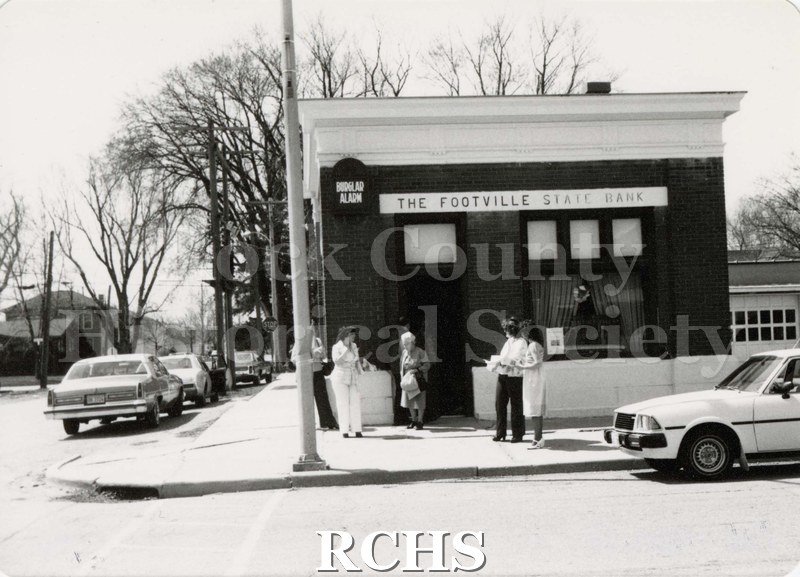Black and white photograph of men and women leaving and standing outside the Footville State Bank.