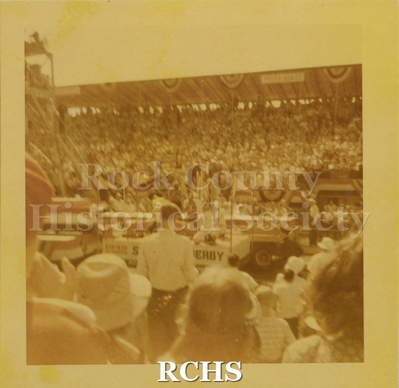Color photo of Akron, Ohio, derby parade from among the crowd in the stands. Taken 1948. Many flags and red, white, and blue decorations.