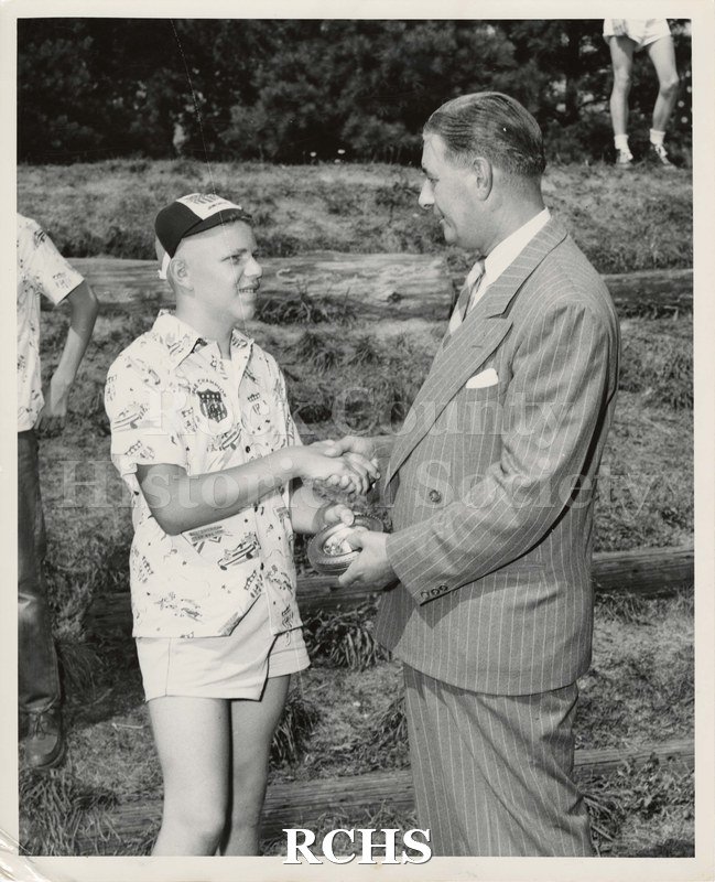 Black and white photograph of Carliss B. Shuler shaking hands with the President or Chairman of the Board of the General Motors Cooperation.
