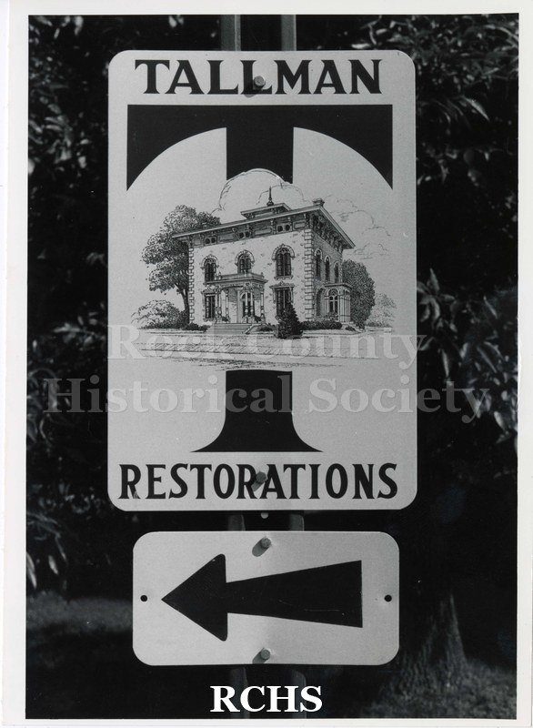 Black and white photograph of sign entitled: "Tallman Restorations" with an arrow pointing left.