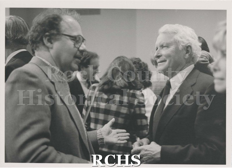 Black and white photograph of Richard P. Hartung (left) and Steven P. J. Wood, (Right). Shows several other people in the background.