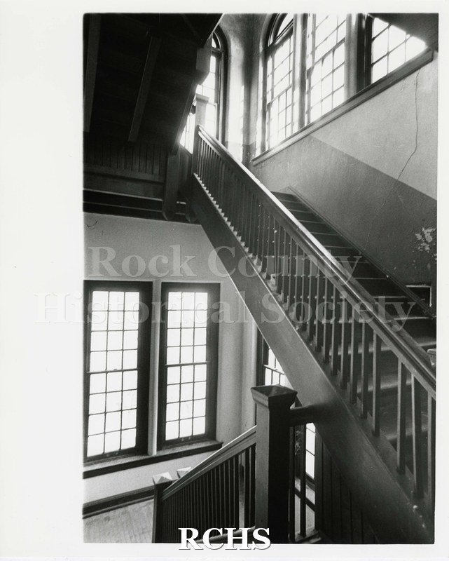 Black and white photograph of stairway in Pearson's Hall. Wall cracked.