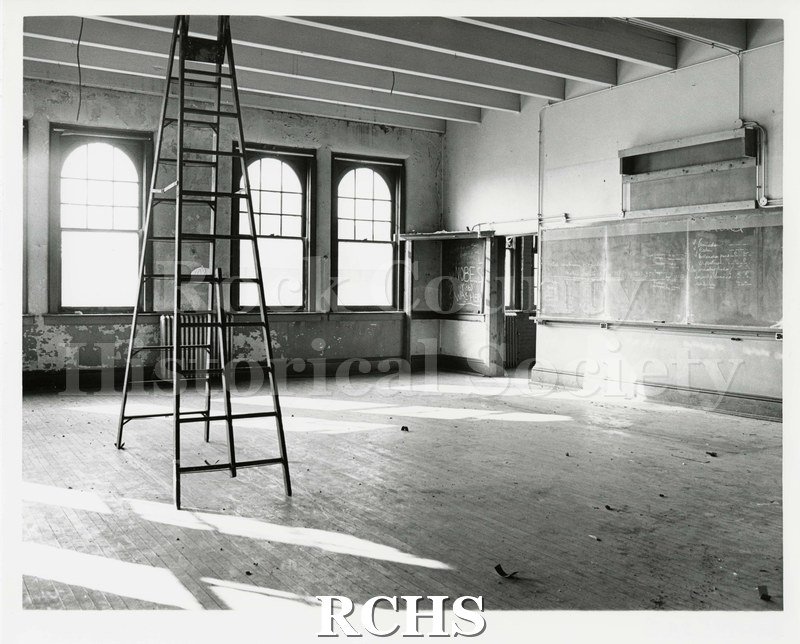Black and white photograph of a room in Pearson's Hall with just a ladder and some mounted chalkboards. The chalkboards are mounted on the wall to the right.