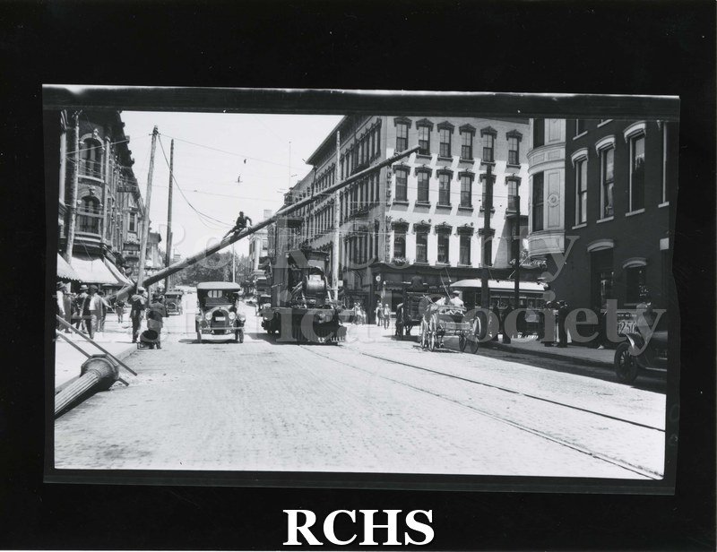 Black and white photograph of Janesville power poles. Shows men installing higher power poles c. 1925.