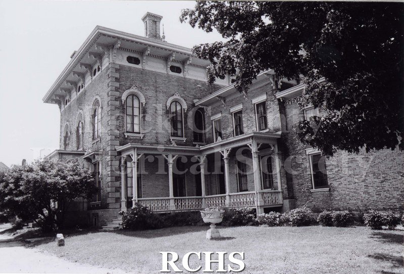 Black and white photograph of Tallman House side exterior by porch. Tree in upper right corner.