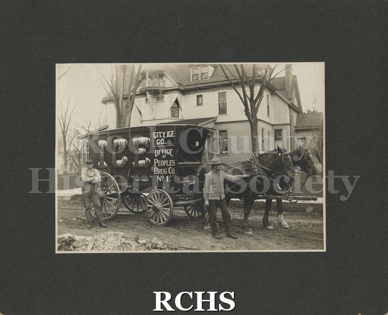 Black and white photograph of City Ice Co. 1909. Shows a team of horses hitched to a wagon. On the wagon is a sign: "City Ice Co. Office at Peoples Drug Co. No. 1".