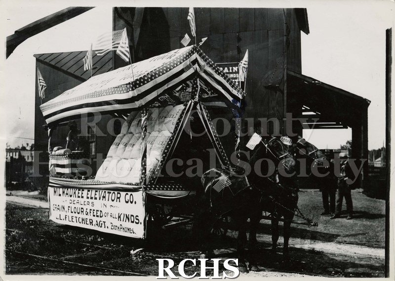 Black and white photograph of a horse-drawn parade float for Milwaukee Elevator Co.