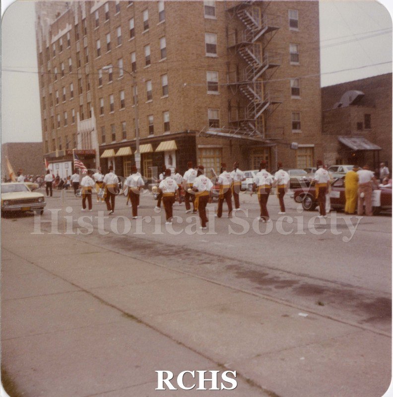 Colored photograph of Shriners marching along side Monterey Hotel, Janesville. Written on reverse: "Shriner's Parade, 1984".