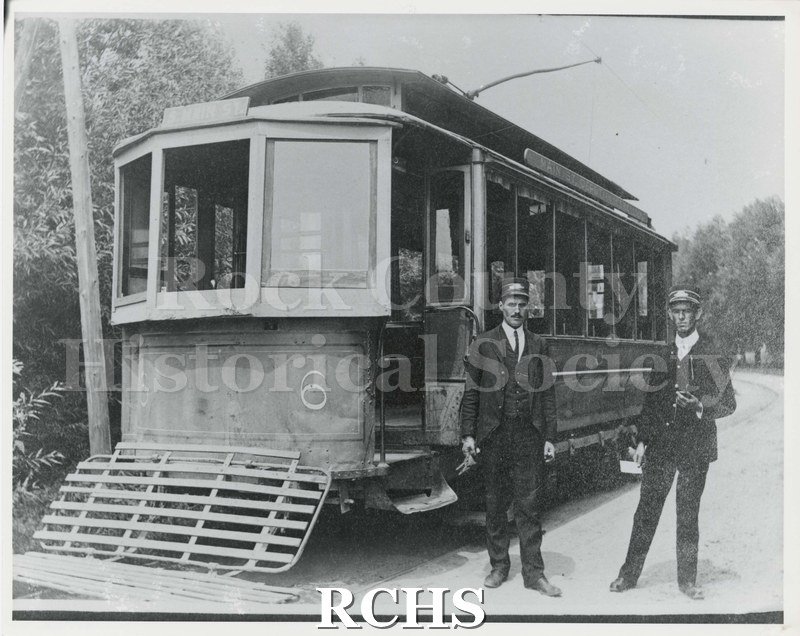 Historic image of Black and white copy print of Janesville Streetcar #6. Shows two men in uniform standing beside the car.