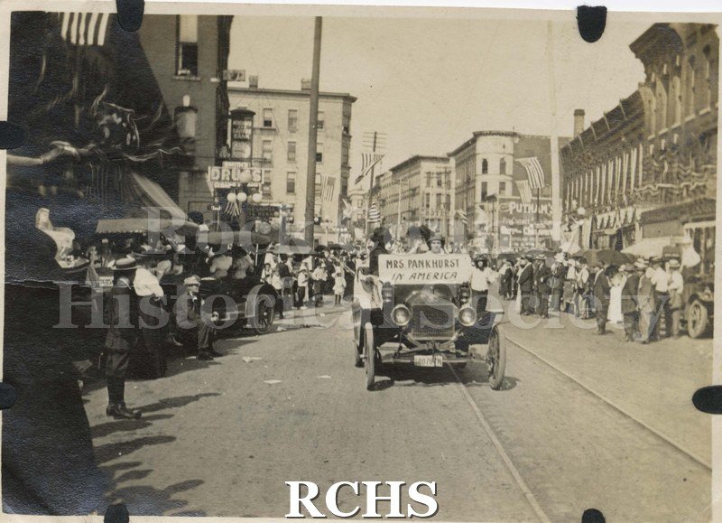 Black and white photograph of Milwaukee Street parade circa 1917 Janesville. Period automobile carrying a sign stating "MRS PANKHURST IN AMERICA".