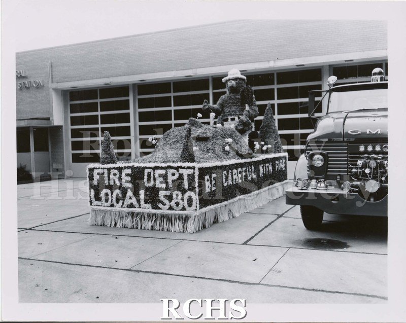 Black and white photograph of the Janesville Fire Dept. Parade Float. The float has Smokey the bear on top. Front of float, "FIRE DEPT/LOCAL 580".