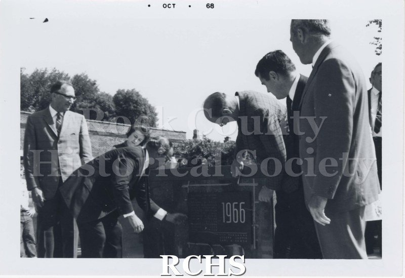 Black and white photograph of five unidentified men standing beside the dedication plaque that reads 1966.