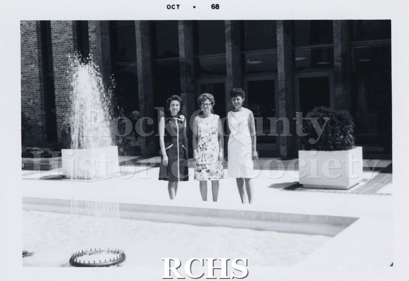 Black and white photograph of three unidentified women standing on the terrace in front of City Hall. All are wearing sleeveless dresses.