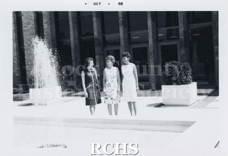 Black and white photograph of three unidentified women standing on the terrace in front of City Hall. All are wearing sleeveless dresses.