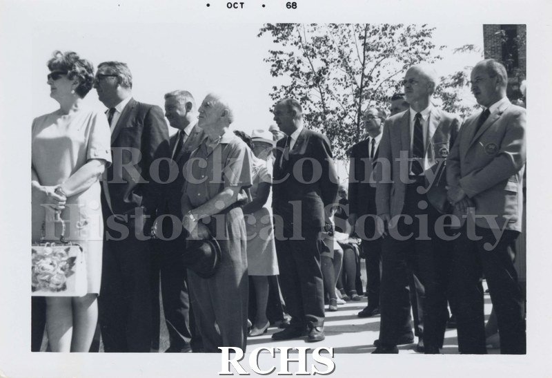 Black and white photograph of several men and women standing at attention, probably listening to a speaker.