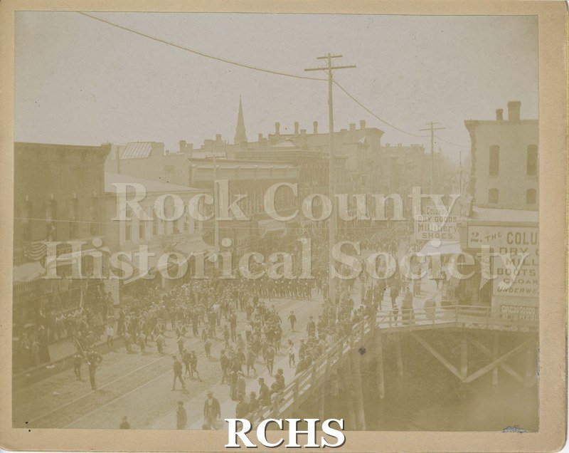 Black and white photograph of uniformed men about to parade across Milwaukee Avenue bridge.