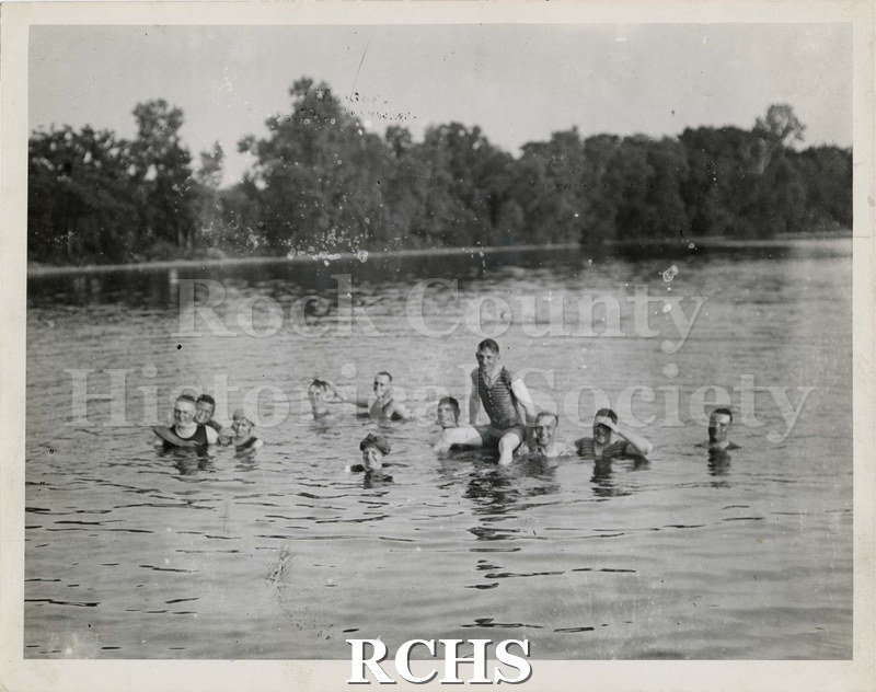 Black and white photograph of bathers in Rock River. There are 11 men and women visible in the river.