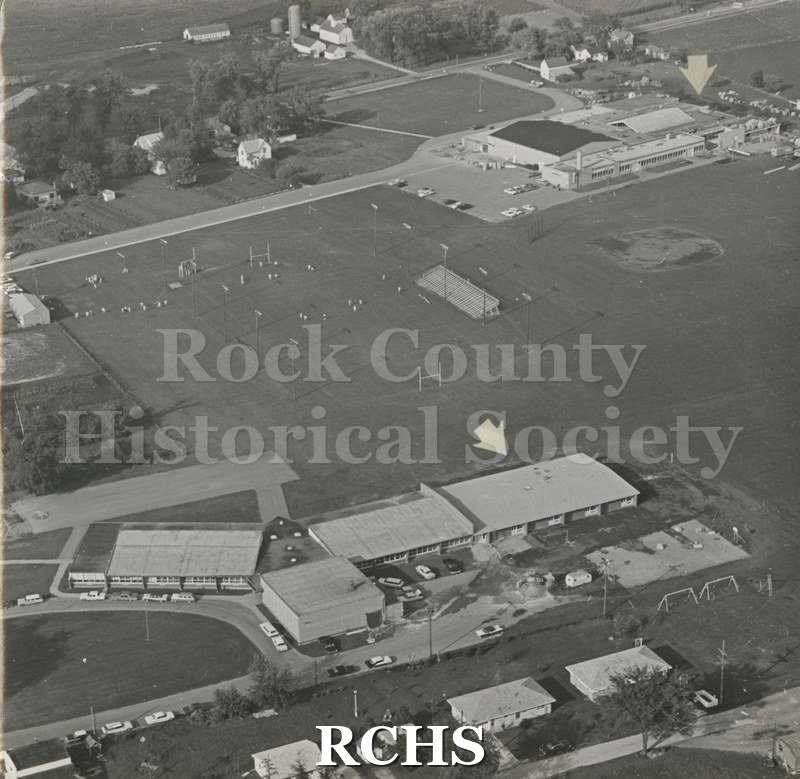 Black and white aerial view of Clinton School addition. There is an arrow pointing to a building. There is a sports field behind the school.