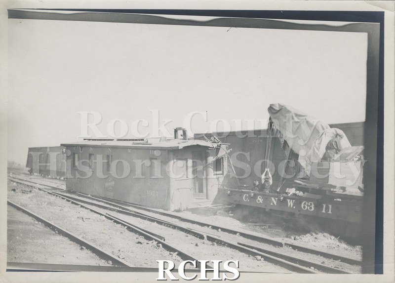 Black and white photograph of a train wreck. The train car reads: "C. & W. 63 11" and is off the track.