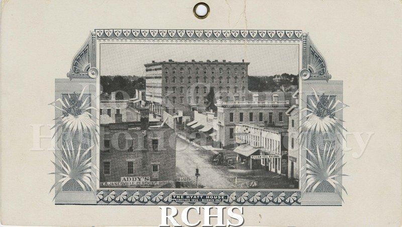 Black and white photograph of the Hyatt House, Janesville, WI. Shows buildings beside hotel, including Addy's Janesville Clothing House and William Tell Saloon.