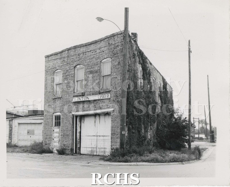 Black and white photograph of the Clinton Township Hall, a brick building. Sign on building reads: "Clinton 1922".