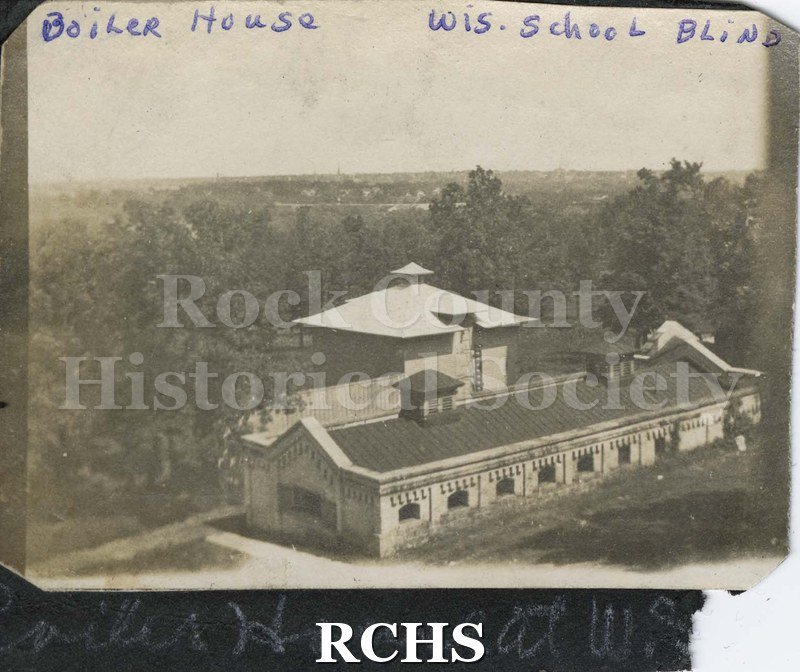 Black and white photograph of the Boiler House Wisconsin School for the Blind. Shows large building with two vents on top of roof.