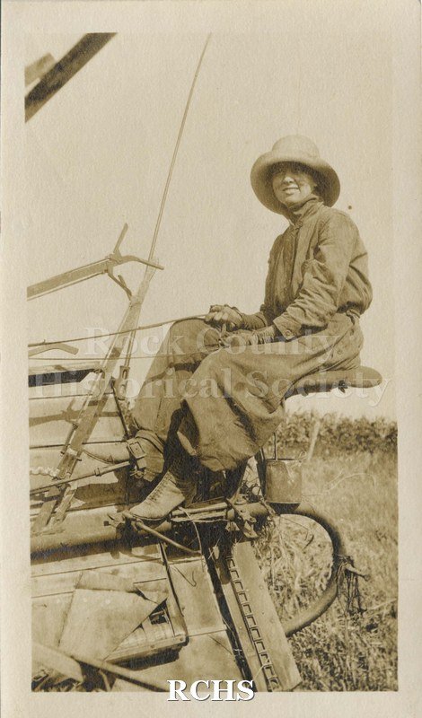 Black and white photograph of Marion McLay on the seat of a threshing machine.