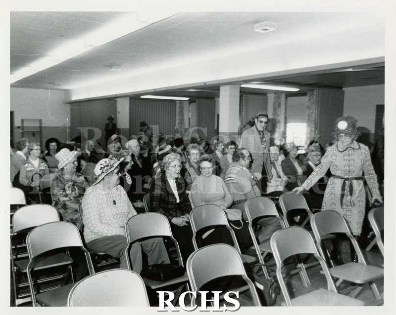 Black and white photograph of the AARP Meeting April 10, 1980. Shows a group of men and women sitting in chairs at a meeting.