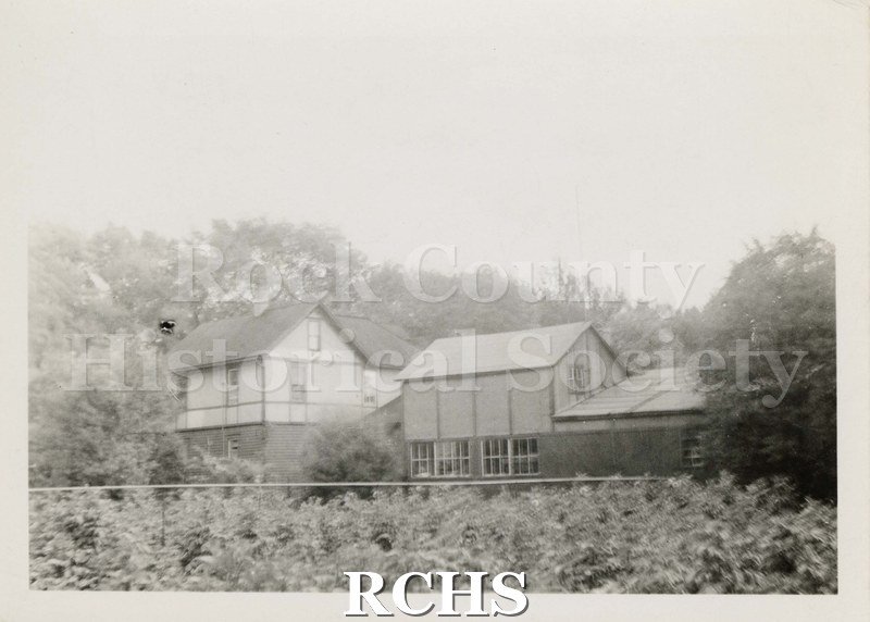 Black and white photograph of Fitchett's Dahlia Gardens.Shows a house with a shop and greenhouse. The gardens are visible in the foreground.