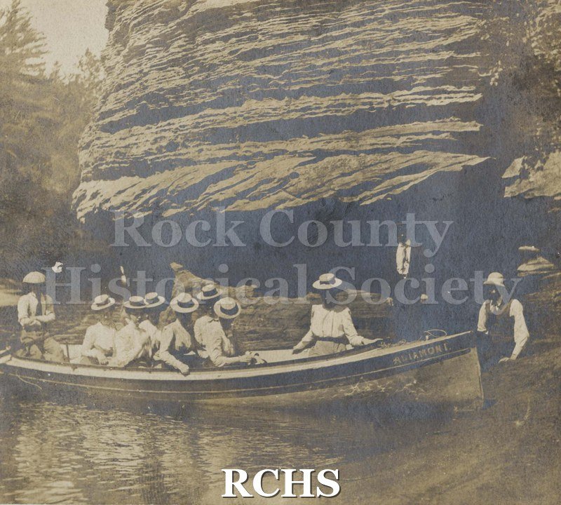 Black and white photograph of canoe filled with men and women, all wearing hats.