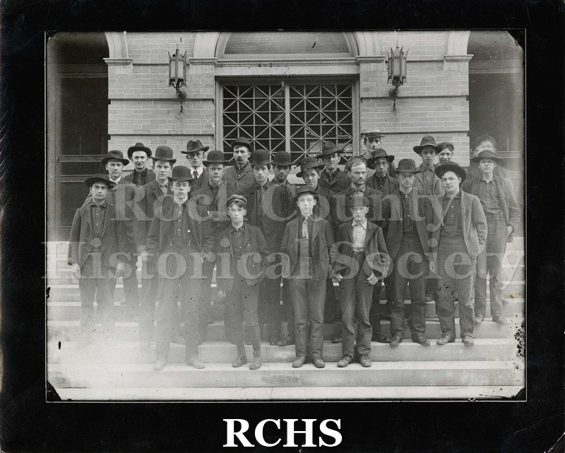 Black and white photograph of Parker Pen Employees. Several men are standing on the steps of the library. Men are wearing dark suits and hats.