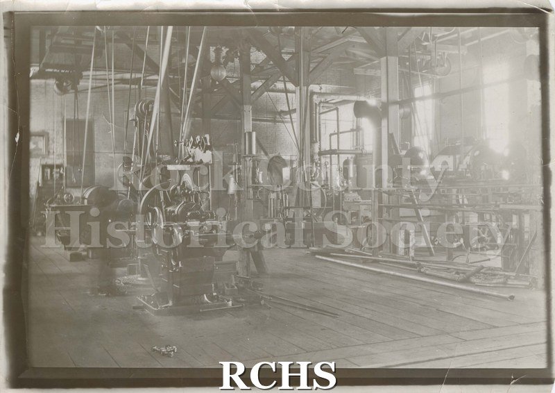 Black and white photograph of Bower City Machine Co. Shows the inside of a factory showing machinery, some with pulleys.