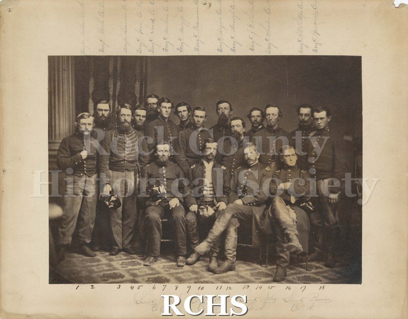 Black and white photograph of Company A, Janesville, WI., Civil War. Shows several men; four are sitting and the others are standing.