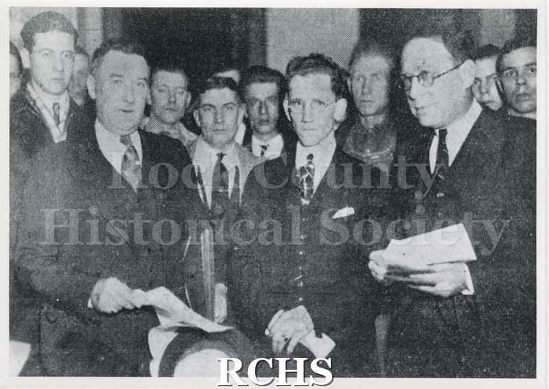 Black and white photograph of Janesville City Hall members shown in newspaper photograph.