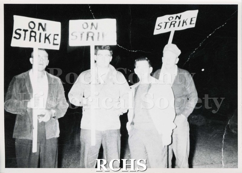 Black and white photograph of GM Pickets 1946. Shows four men on strike. Three are carrying signs that read: "On Strike". One is not.