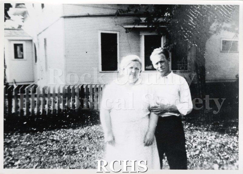 Black and white photograph of Gerald Litney and his mother in front of a house with a fence in front of it.