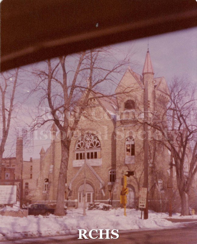 Colored photograph of the First Baptist Church in the winter time. There is snow on the ground and the trees are bare.