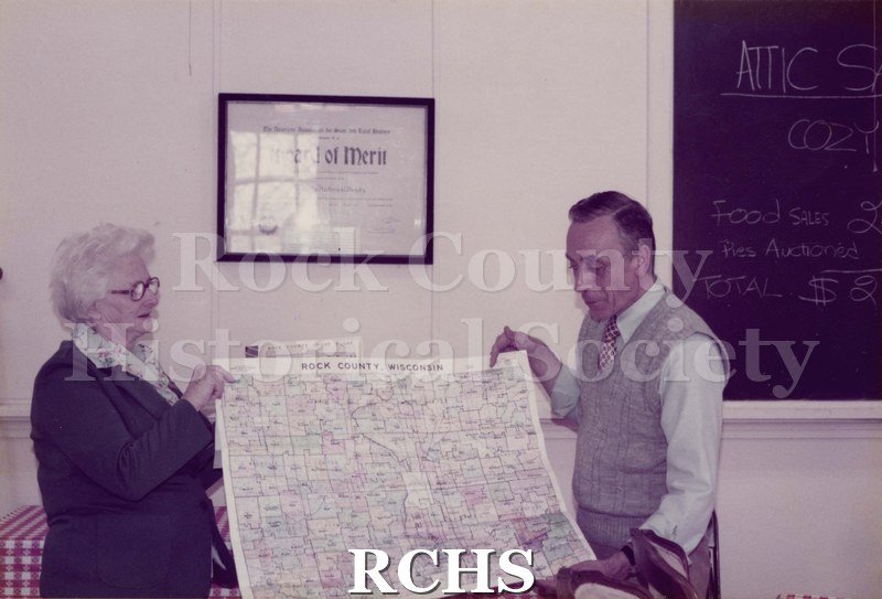 Colored photograph of Mildred Rye and Maurice Montgomery holding a map.