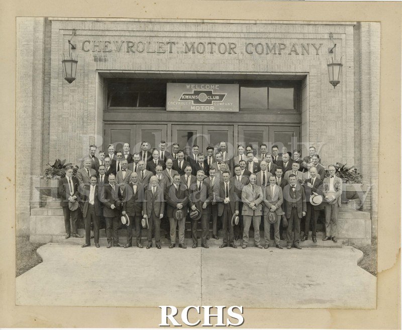 Black and white photograph of the Kiwanis Club at GMAD showing a group of men standing in front of a building.