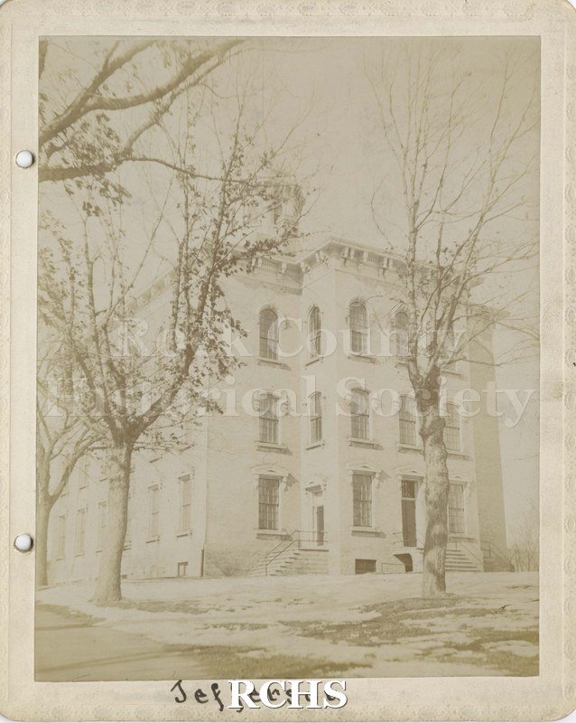 Black and white photograph of Jefferson School, Janesville, WI. Shows a three story building with bare trees in front. On bottom: "Jefferson".