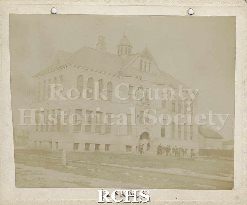 Black and white photograph of Grant School, Janesville, WI. Shows a two story building with children in front of it. On bottom: "Grant".