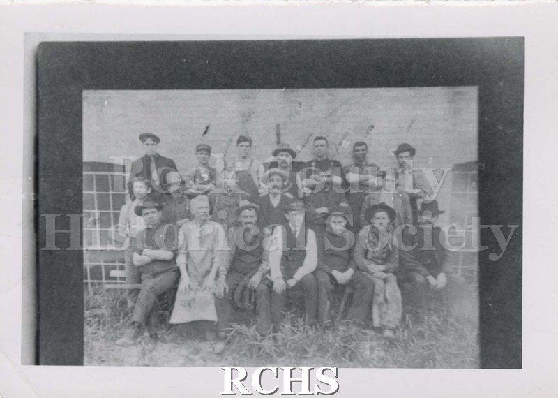 Black and white photograph of Janesville Carriage Works. Shows several people posed in front of a building.