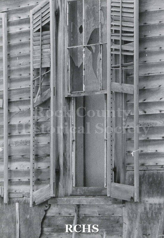 Black and white photograph of Hodson House, Shopiere Road. Shows a broken window and broken shutters.
