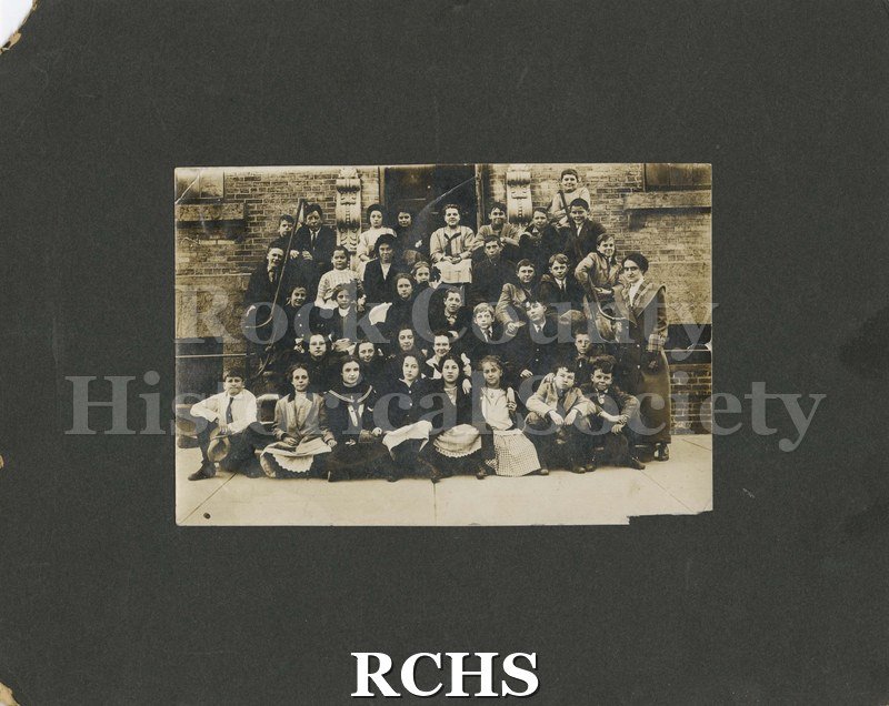 Black and white photograph of Jefferson School, Janesville, WI. School children are posing in front of a school.
