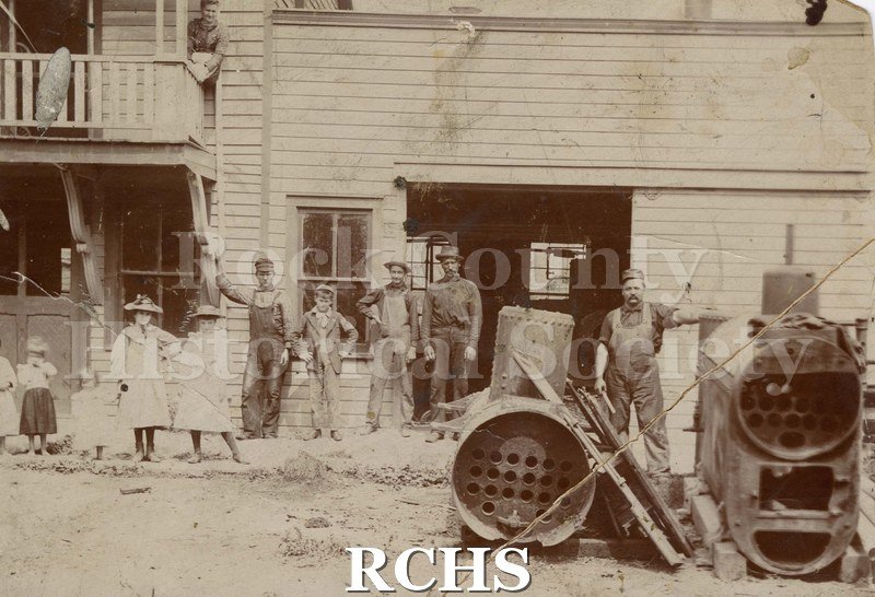 Photo. Black and white photograph of Ambrose Boiler Works. Shows several men, women and children posed in front of a factory.