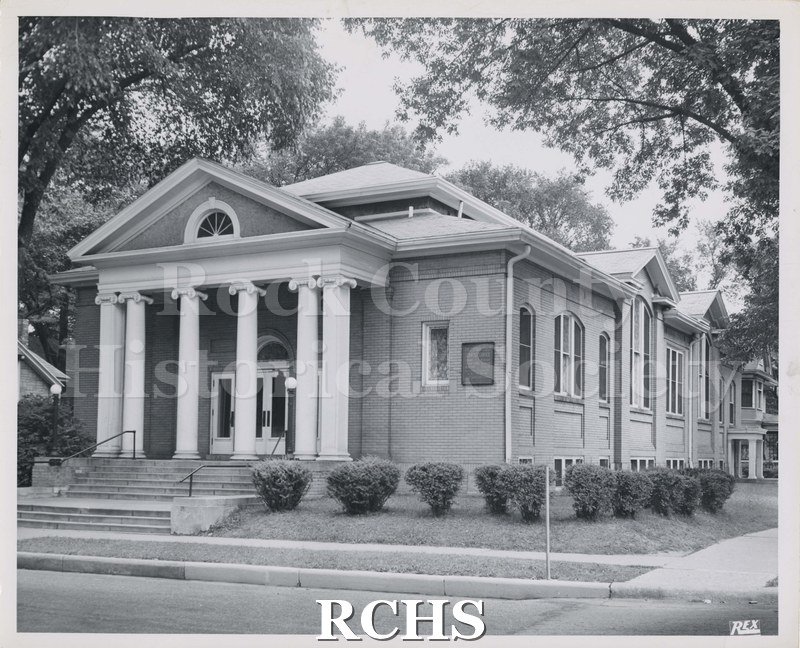 Black and white photograph of First Church of Christ Scientist, Janesville, WI. Shows a brick church with four pillars in front of the doors.